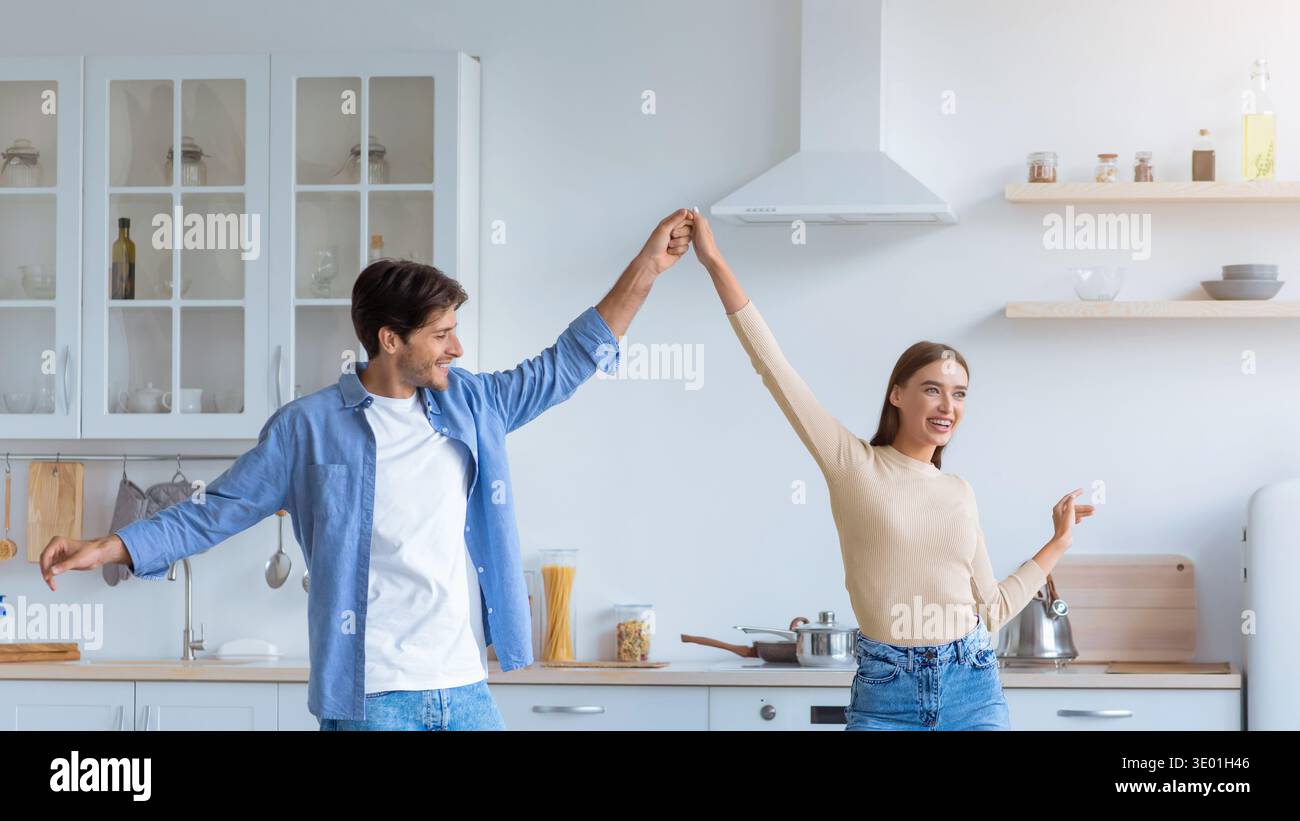 Couple Enjoys a Fun Dance in Their Bright Kitchen While Cooking Together Stock Photo