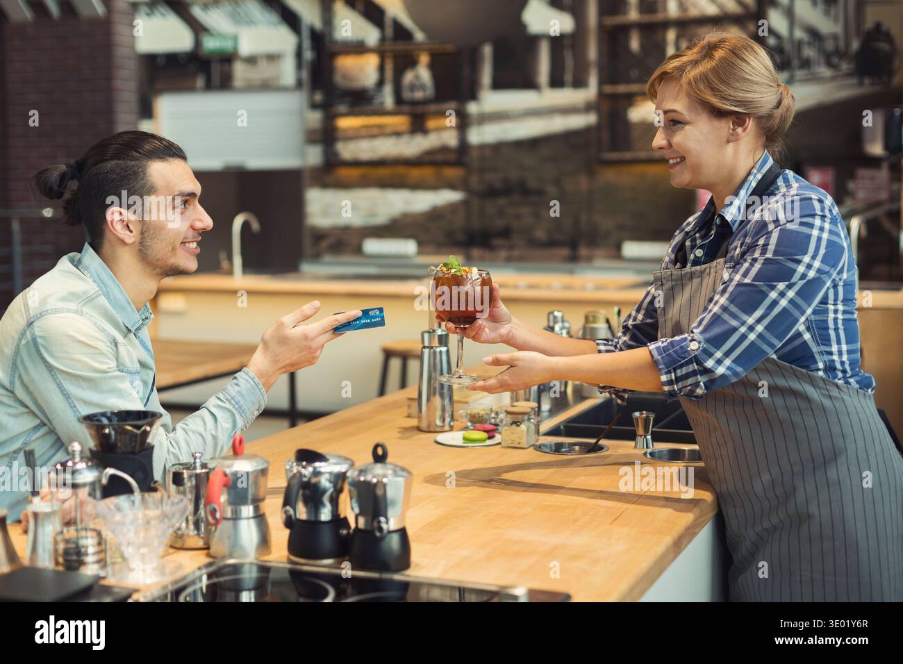 Smiling barista taking payment from client Stock Photo
