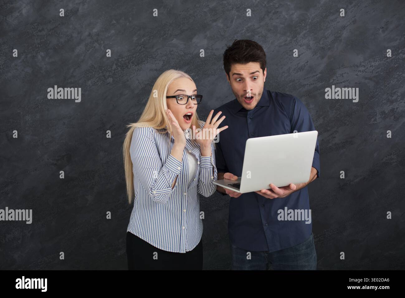 Shocked business partners using laptop at studio Stock Photo