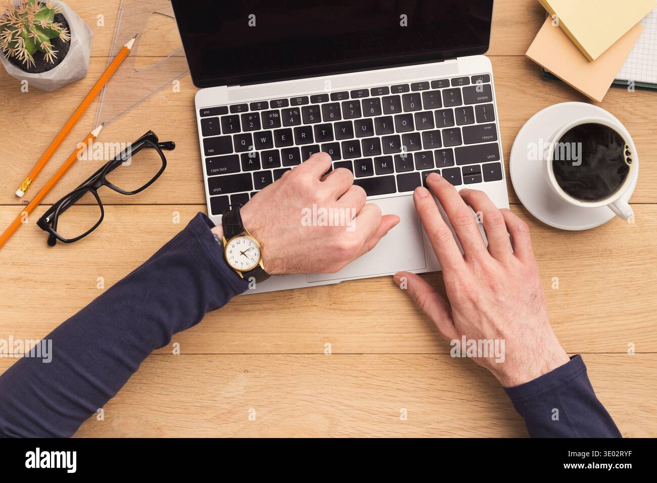 Man typing on laptop computer on wooden table. Stock Photo