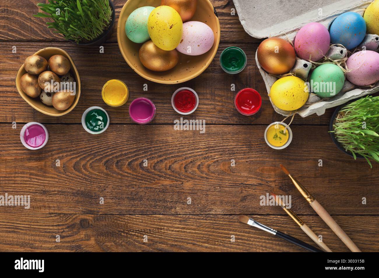 Painted easter eggs and brushes on wooden table Stock Photo