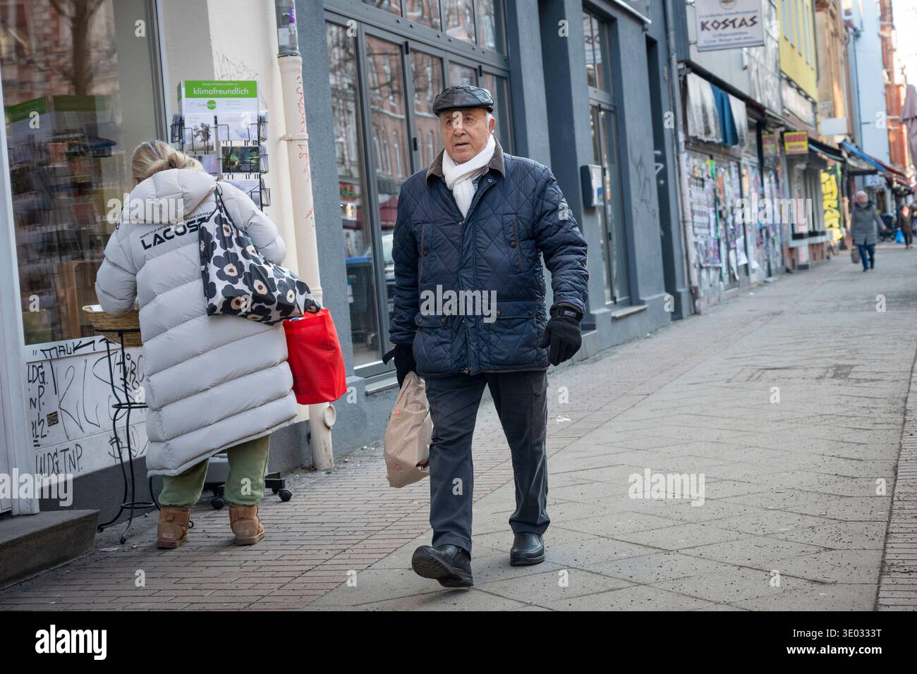 Older man in quilted jacket  walking on Limmerstrasse, Hannover, Germany Stock Photo