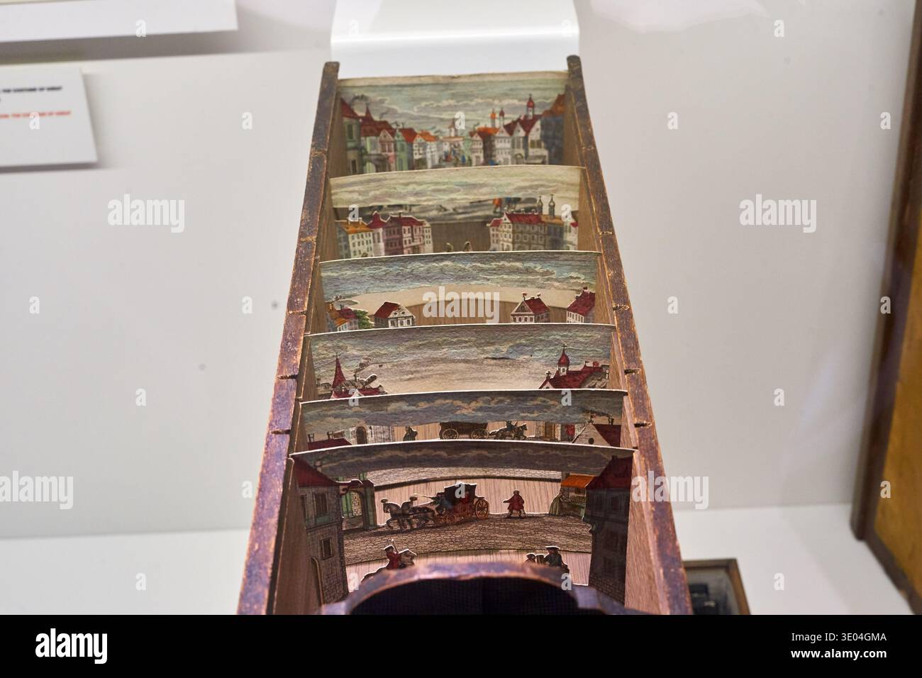A close-up view of a historical perspective theater (peep show box) displayed in a museum setting. The wooden box contains multiple layered panels... Stock Photo