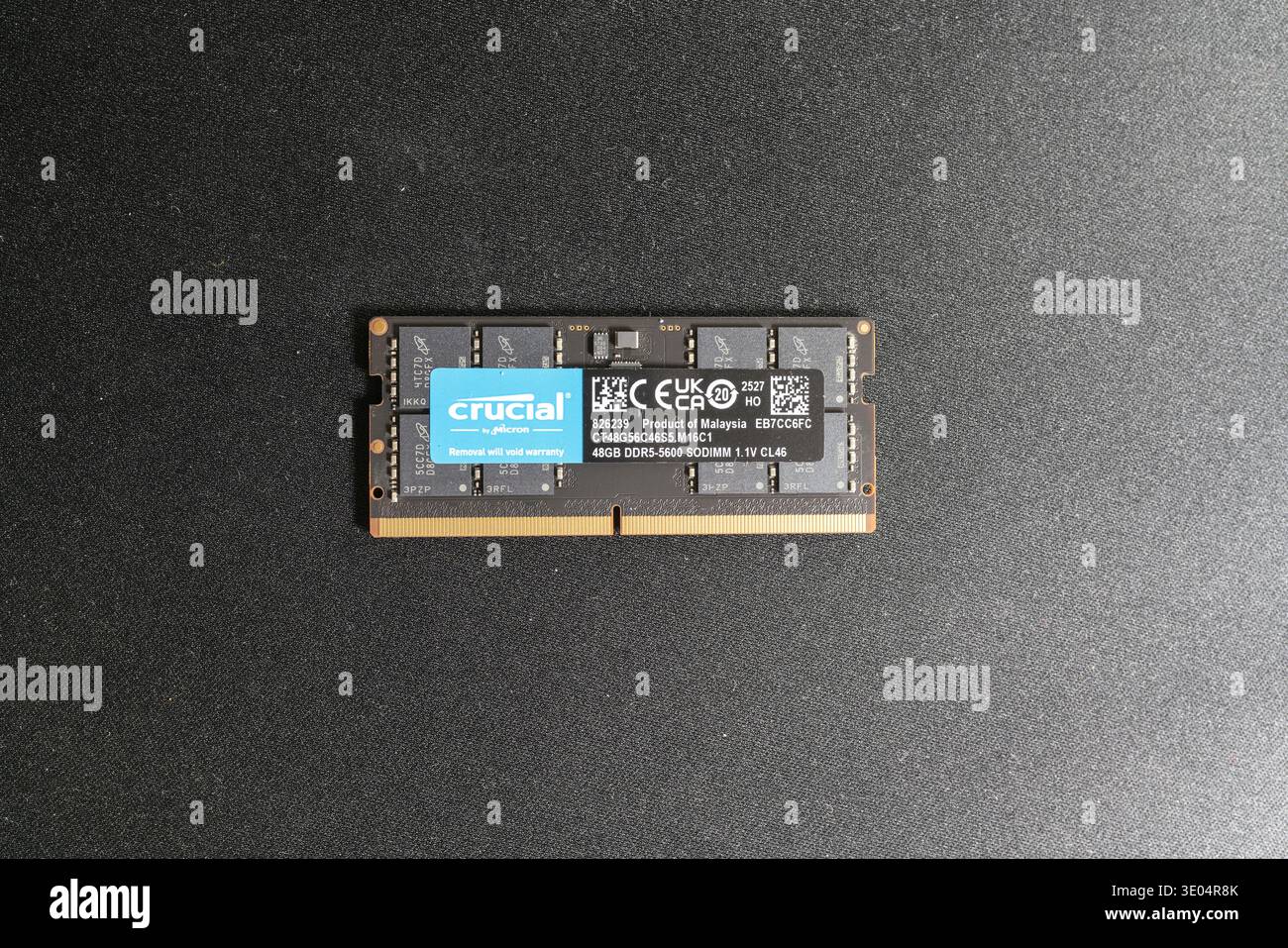 Close-up of a Crucial by Micron DDR5-5600 SO-DIMM memory module, 48GB capacity, labeled as product of Malaysia, displayed against a dark textured surf Stock Photo