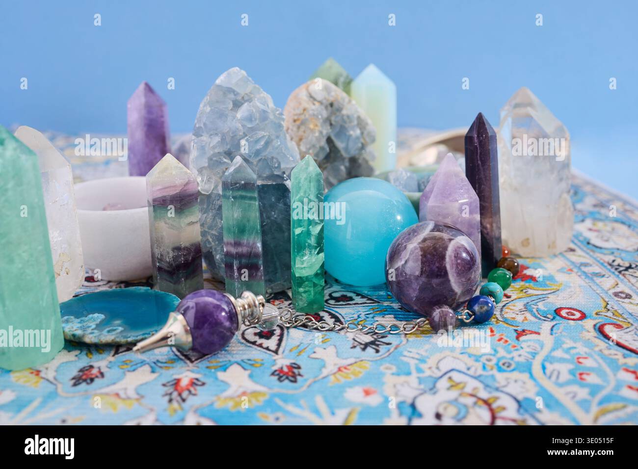 Healing crystals and pendulums arranged on patterned carpet Stock Photo