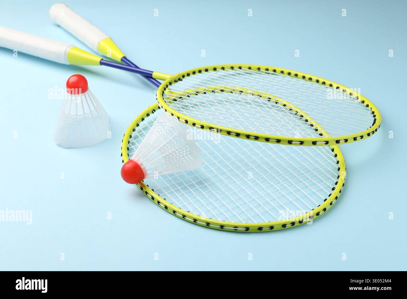 Badminton shuttlecocks and rackets on light blue background Stock Photo