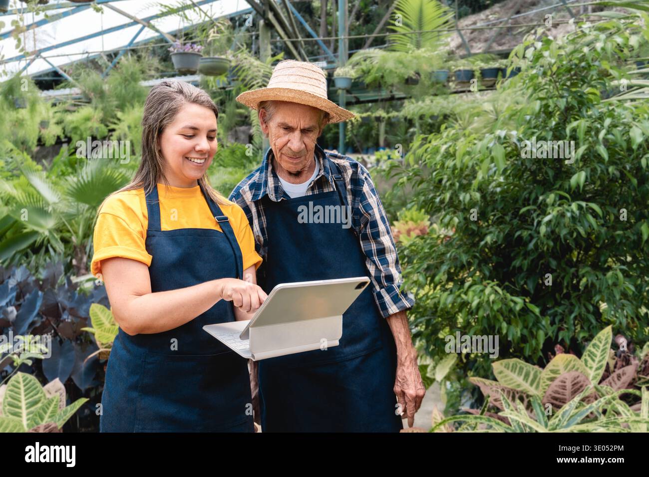 Multigenerational people work at greenhouse doing plants inspection with tablet - Small business farming and e-commerce. Farmers use digital technolog Stock Photo