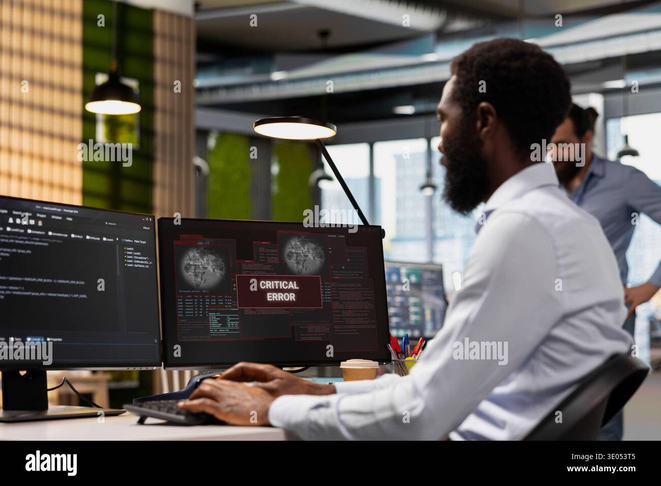 Engineer resolving critical error alert on screen in tech startup office, troubleshooting system warnings. IT professional addressing critical failure message, debugging office equipment Stock Photo