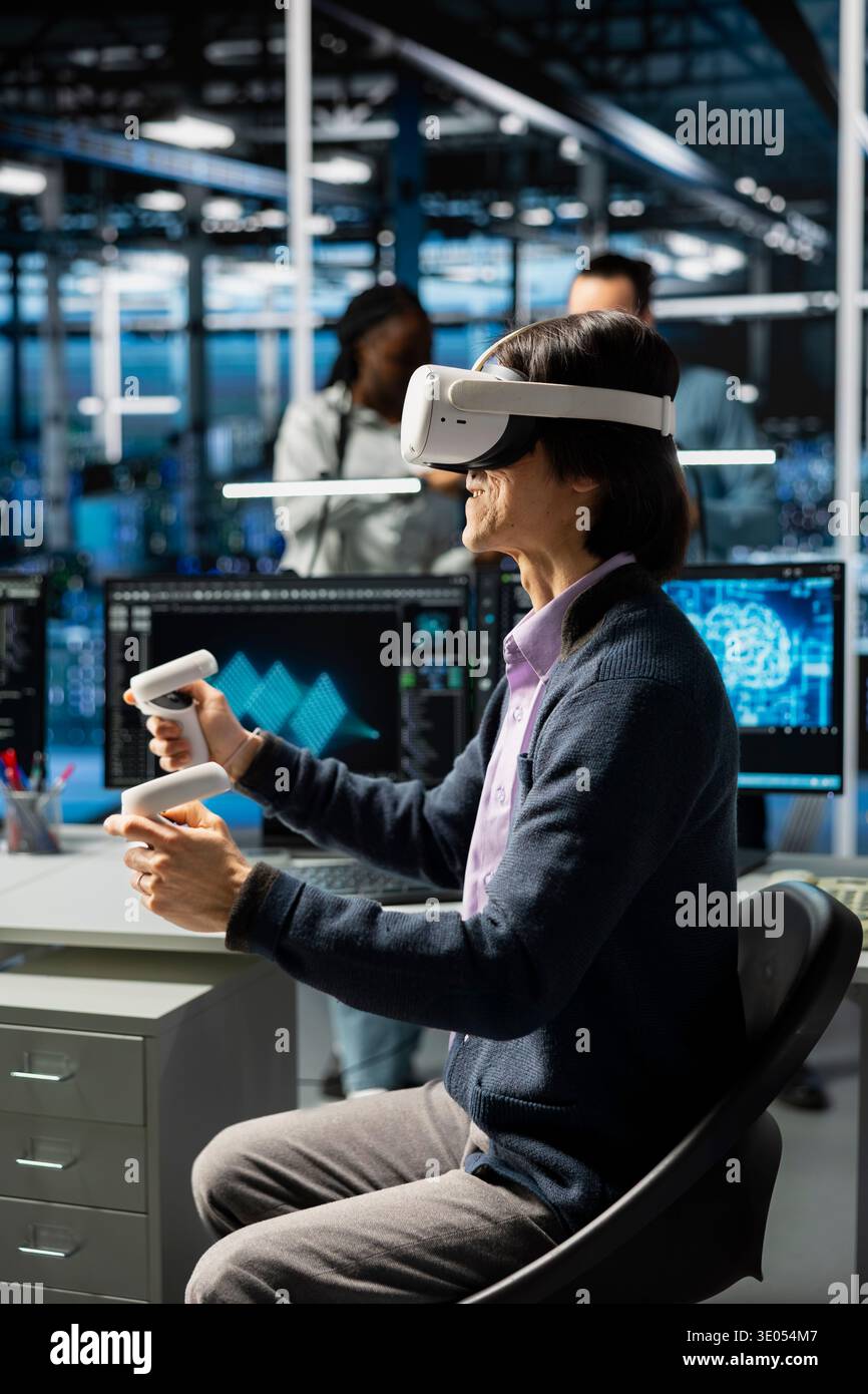 Developer wearing VR headset coding in data center, updating AI automation scripts. Server room employee using virtual reality, programming artificial intelligence algorithms Stock Photo
