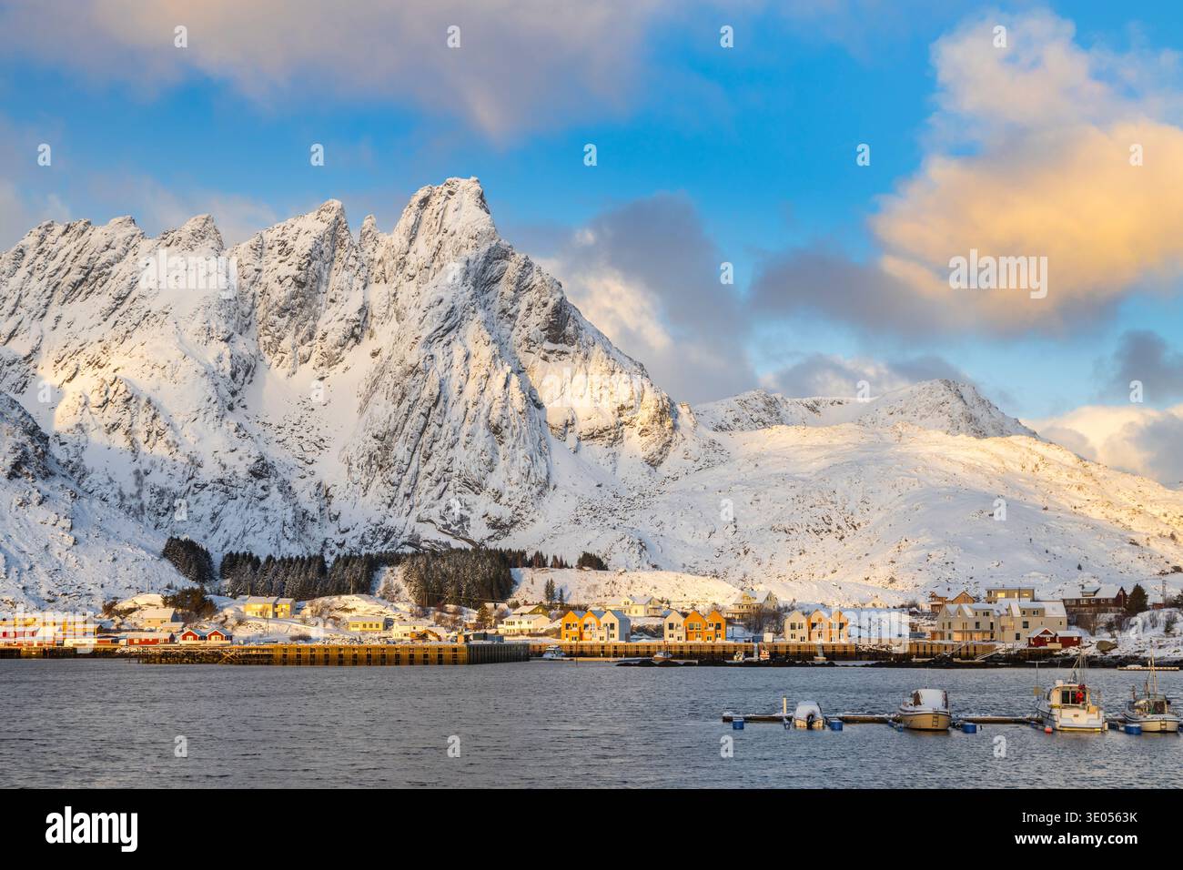 Sunrise view over the rocky peaks and the frozen water of the Ballstad marina. Ballstad, Vestvagoy, Lofoten Islands, Nordland, Norway, Scandinavia. Stock Photo