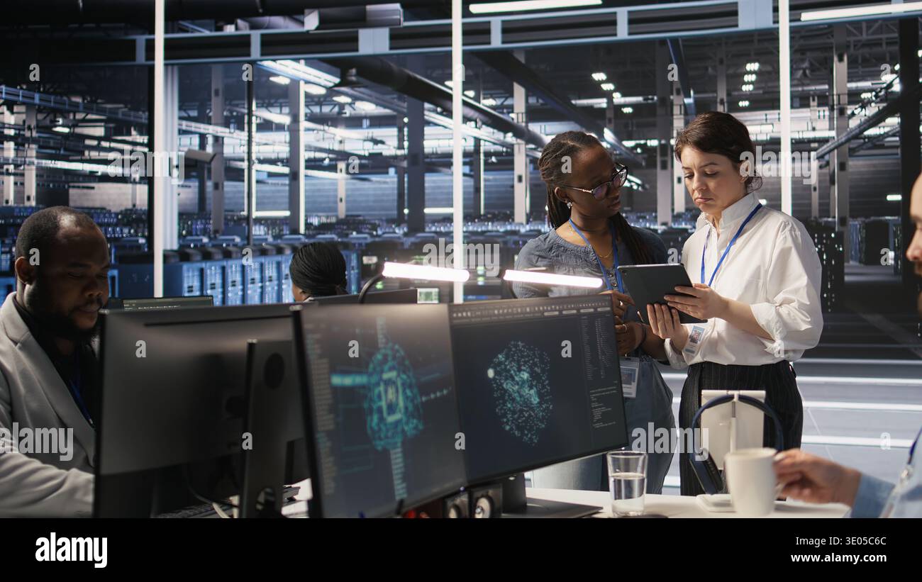 Data center teamworking colleagues performing maintenance on server racks used for artificial intelligence processing. Engineering team managing server hub rigs used for machine learning, camera A Stock Photo