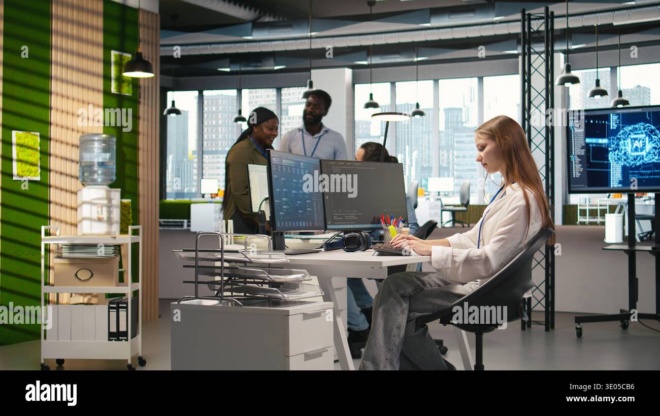 Manager supervising young trainee in office using AI technology, monitoring performance dashboards. Team leader overseeing work done by junior dev tuning neural networks using tools on PC, camera A Stock Photo