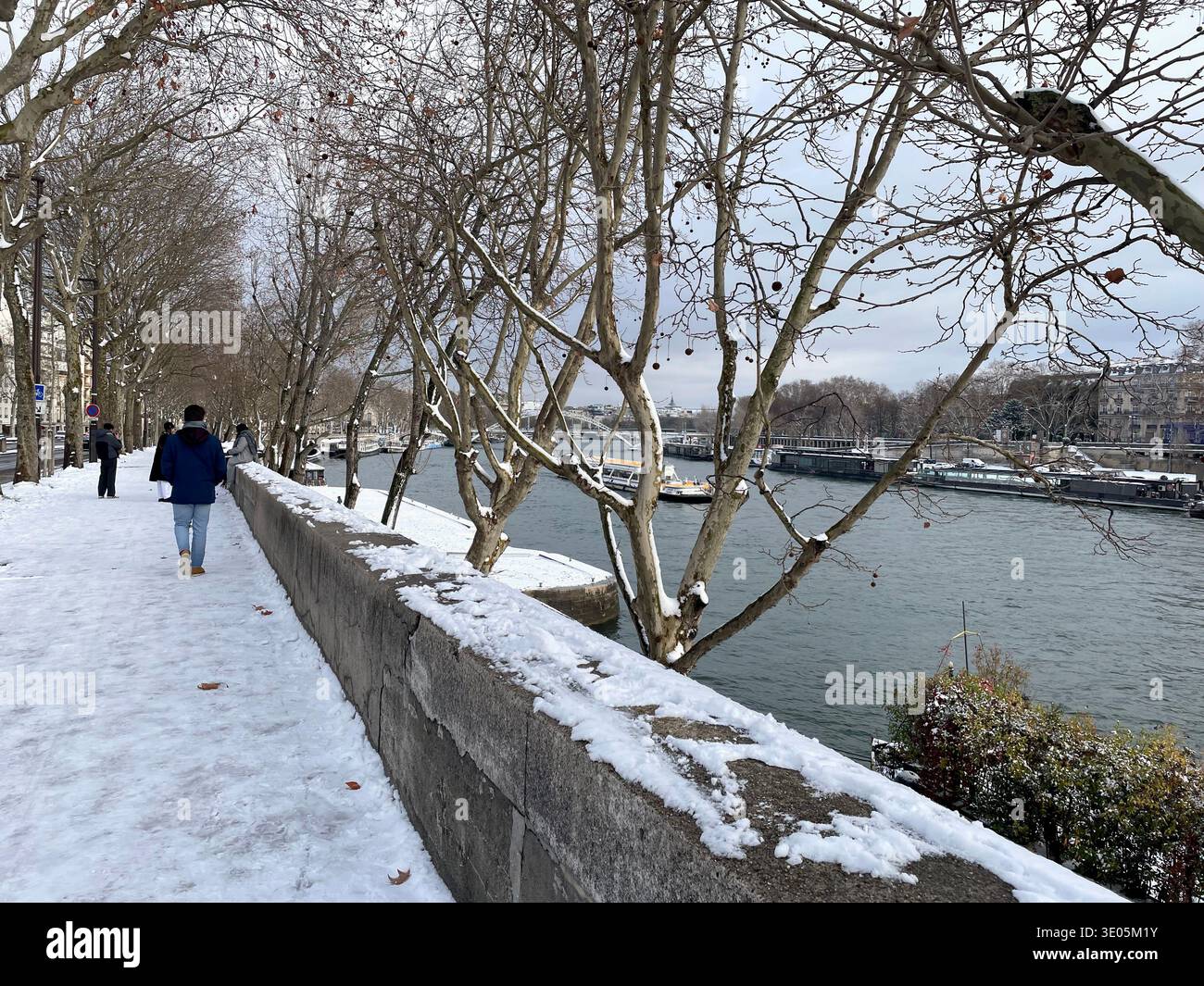 Paris, France. People walking along the quays of the Seine in a snowy winter day. - Smartphone Captured Stock Image