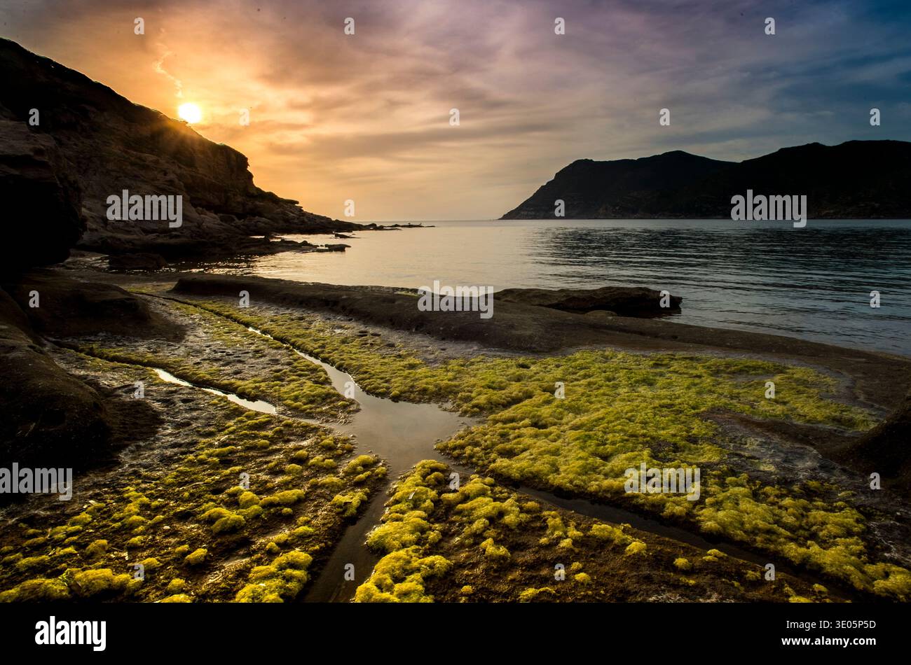 A serene coastal sunset, on a rocky coastline. Porto Ferro, Alghero, Sardinia, Italy Stock Photo