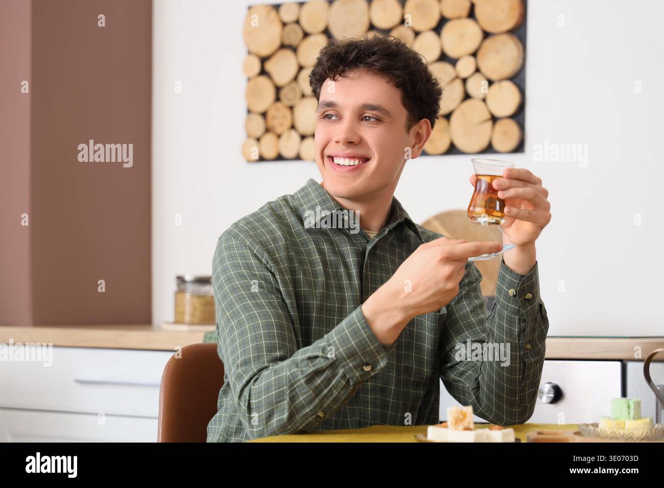 Young man with Turkish tea at table in kitchen Stock Photo