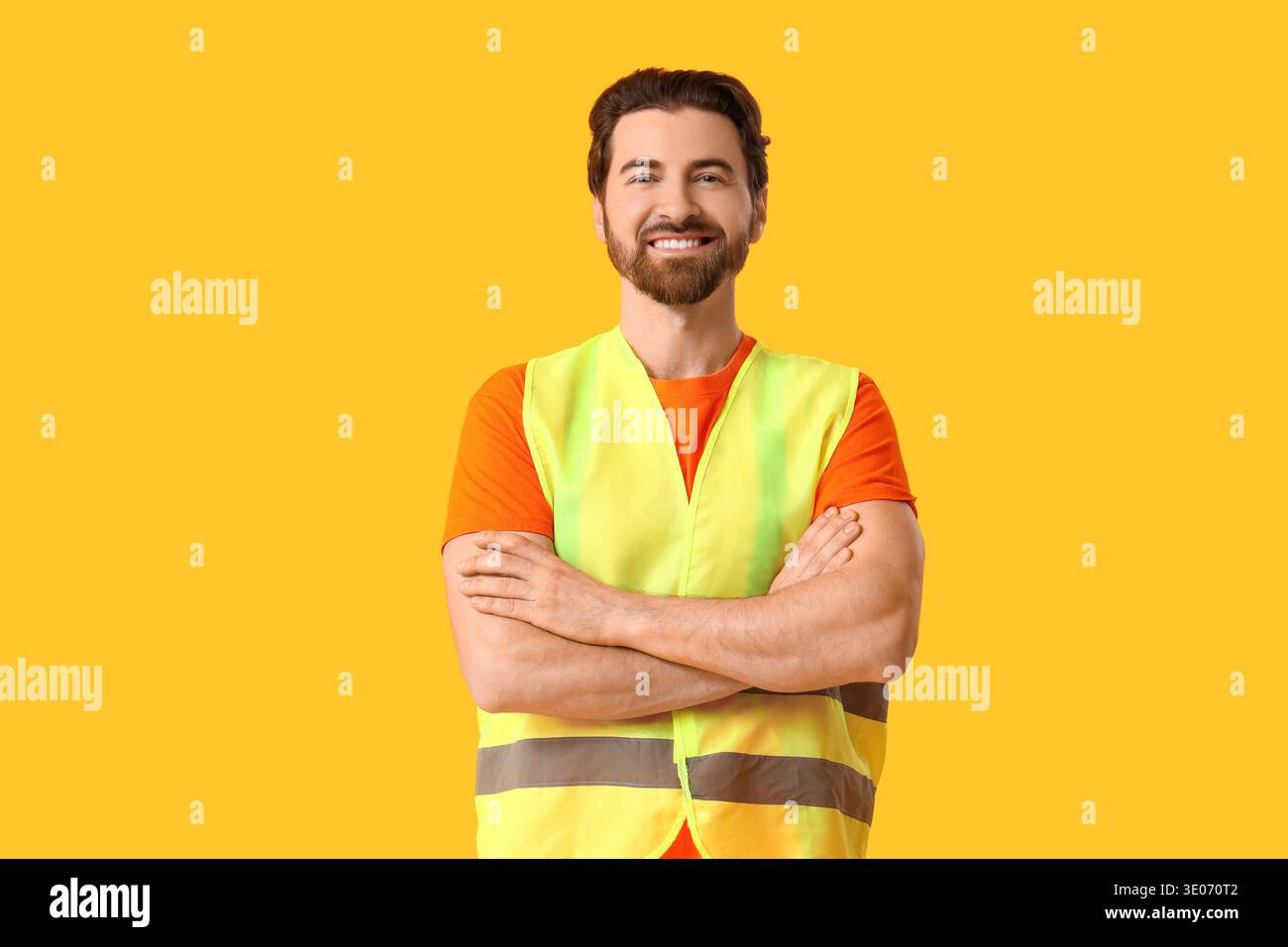 Young happy male construction worker in uniform on yellow background Stock Photo