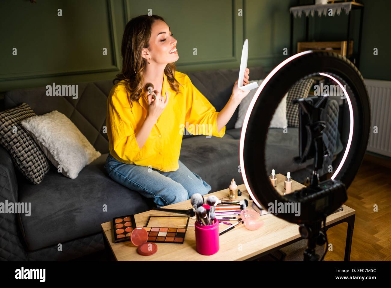 Influencer recording a beauty routine at home. She is using ring light and smartphone. Stock Photo