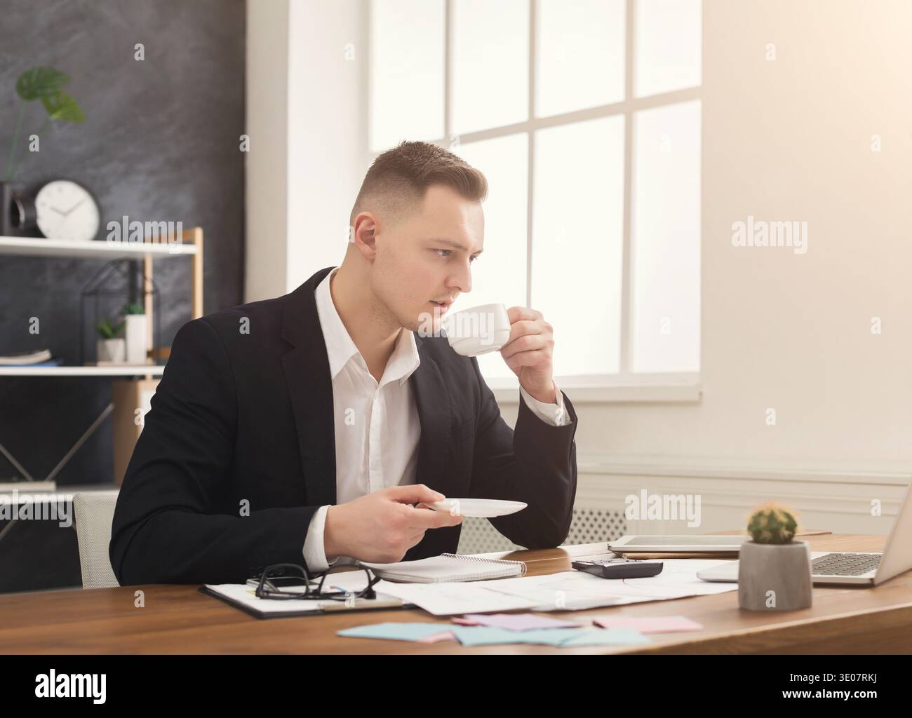 Young male manager working with papers and drinking coffee Stock Photo