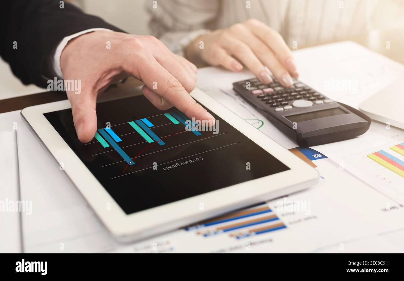 Colleagues counting finances on tablet and calculator Stock Photo