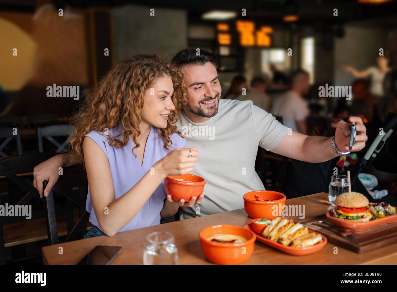 Young couple taking selfie while having lunch at restaurant Stock Photo