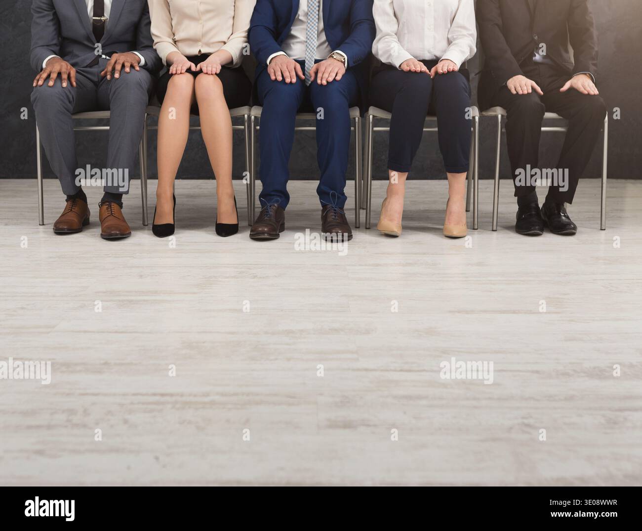 People sitting with hands on knees in a row Stock Photo - Alamy