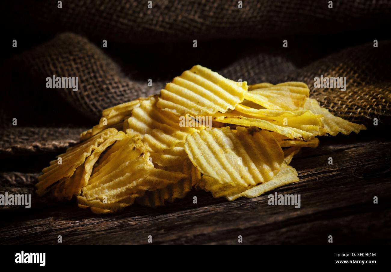 Crispy Potato chips on rustic wooden table. Stock Photo