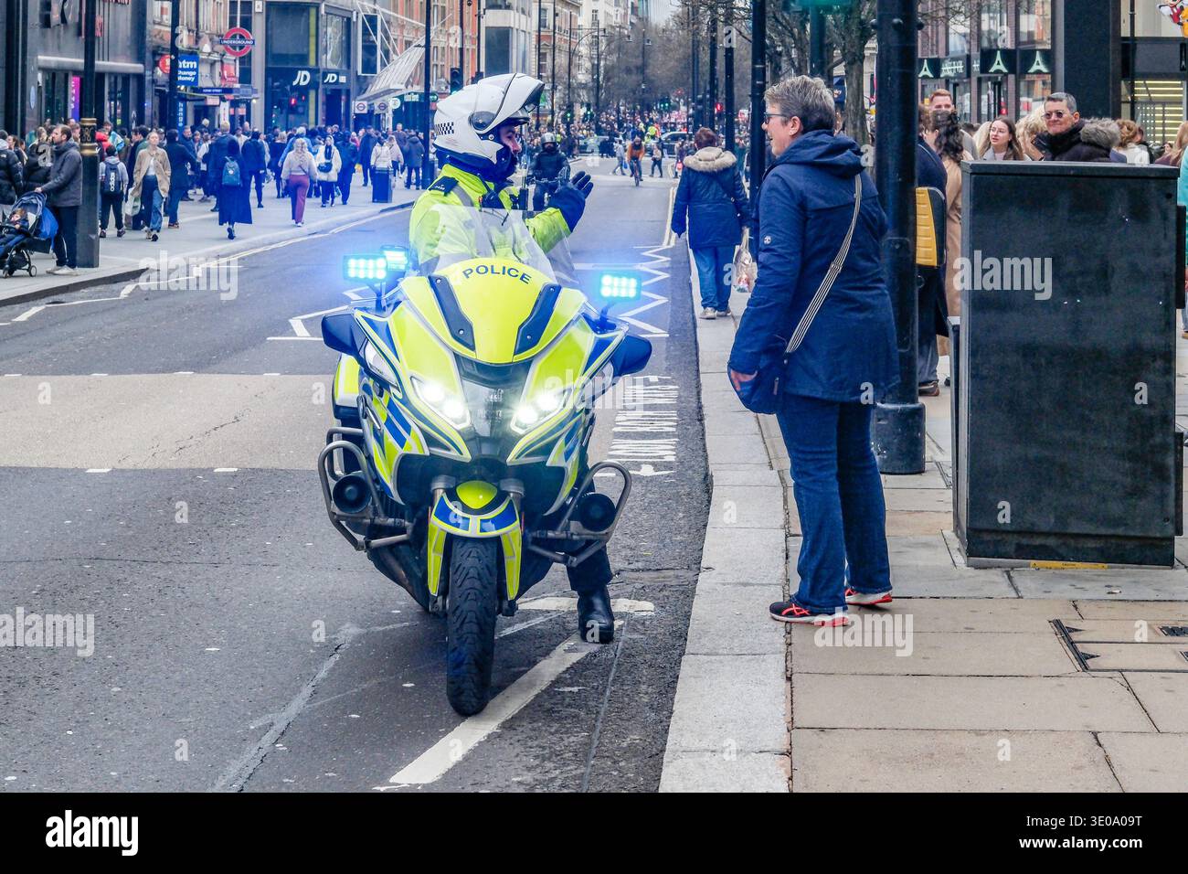 Metropolitan Police officer on motorcycle speaks to a female member of the public at kerbside. London, UK Stock Photo