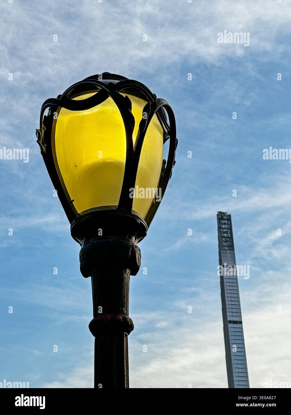 An art deco streetlight in Central Park is located against a small part of the New York City skyline. Stock Photo