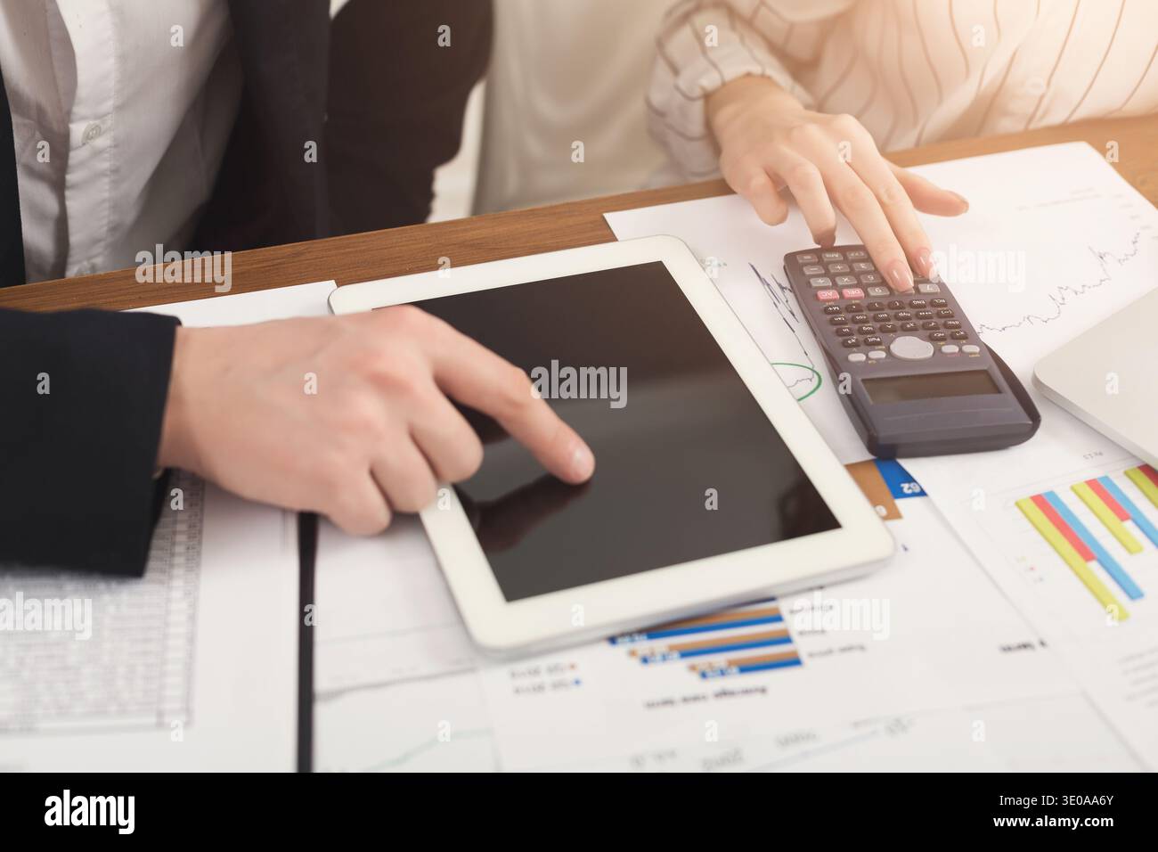 Business colleagues counting on calculator and using tablet Stock Photo