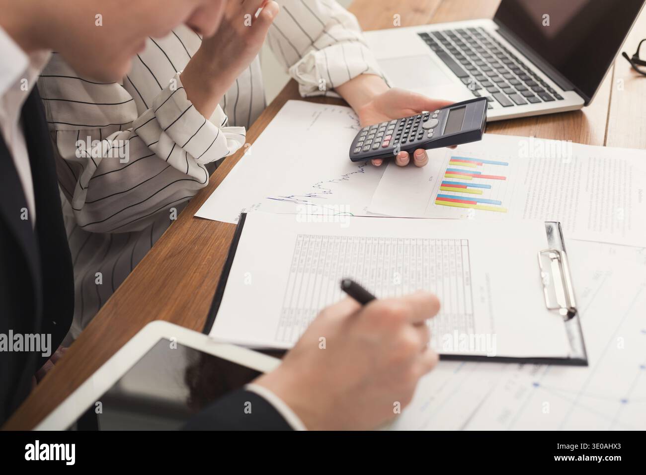Business colleagues checking documents and using calculator Stock Photo