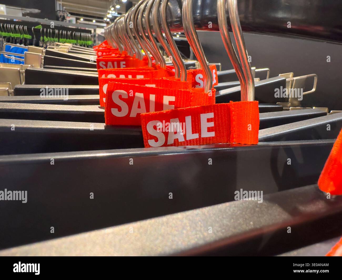 Close-up of red sale tags on black clothing hangers in a retail fashion store department - Smartphone Captured Stock Image
