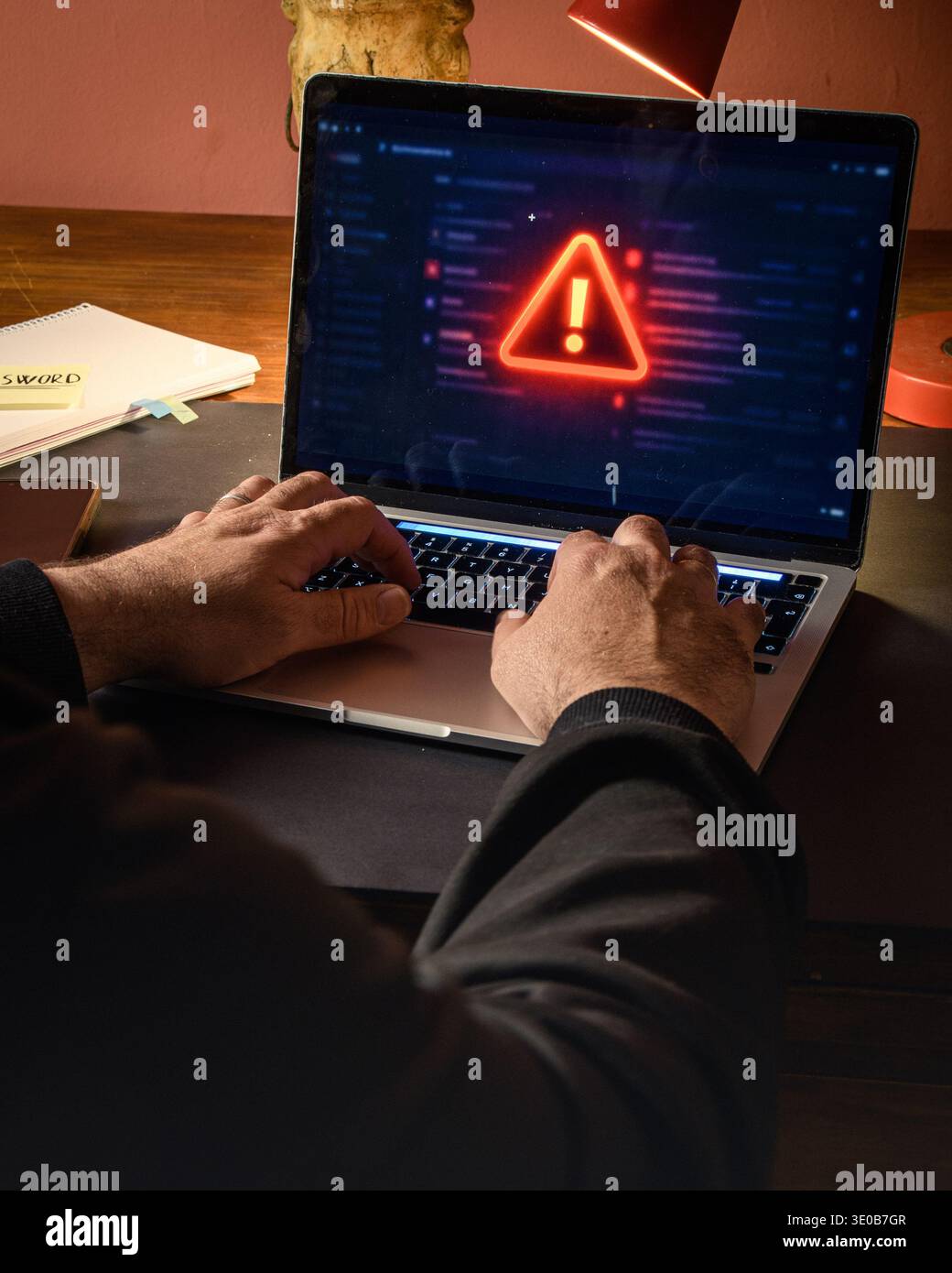 Hands on a laptop with a red warning alert on screen, conceptual image ...