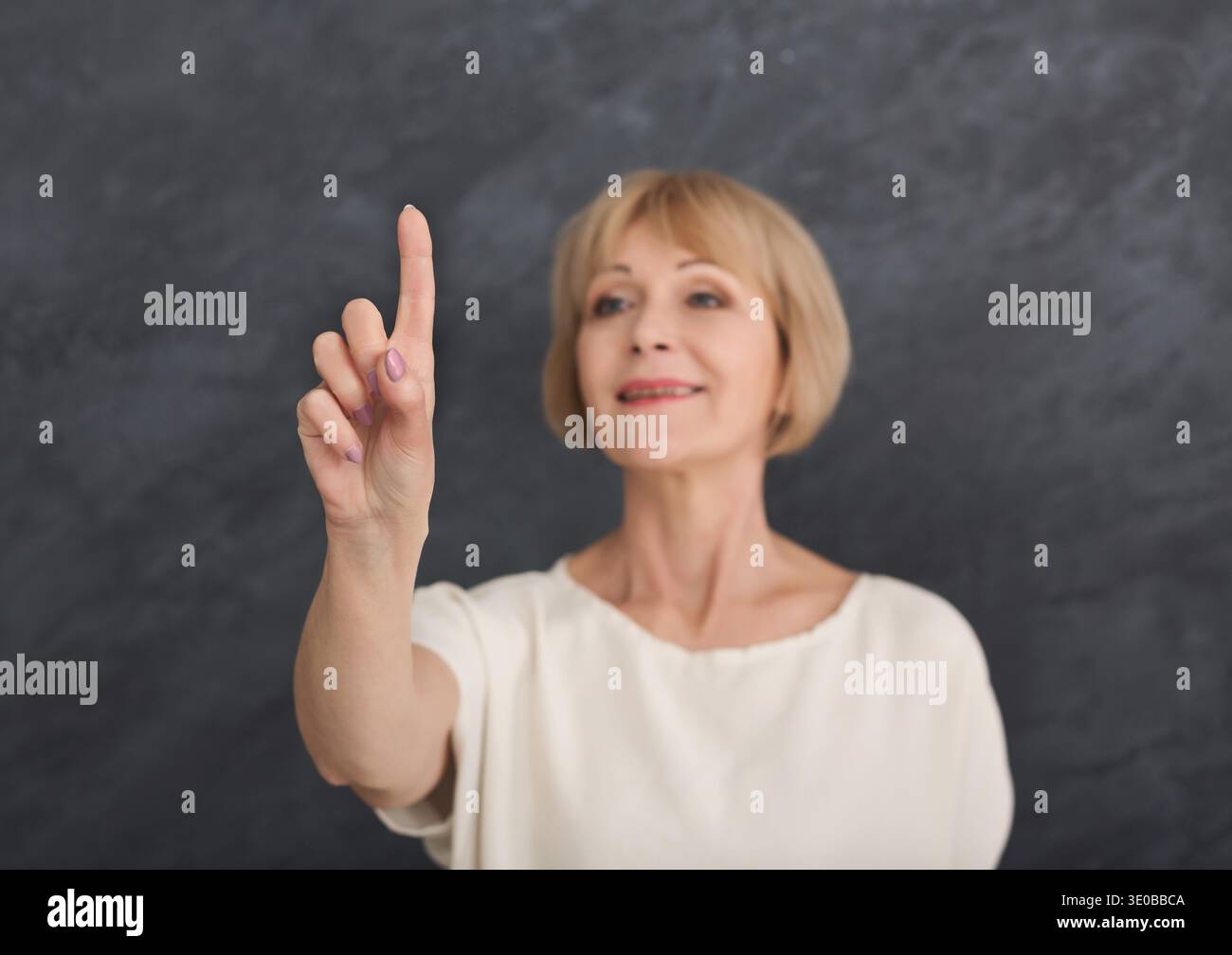 Middle aged woman pointing on invisible object Stock Photo
