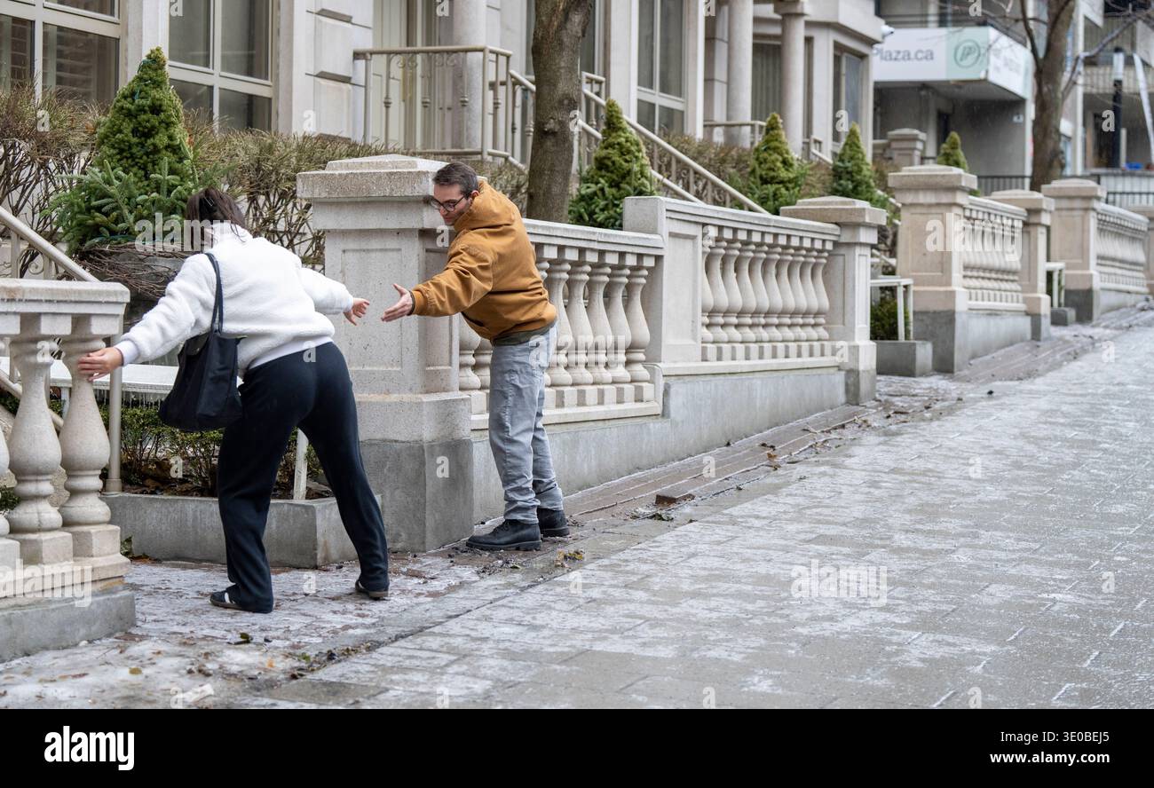 A woman is helped up an icy sidewalk as freezing rain falls in Montreal ...