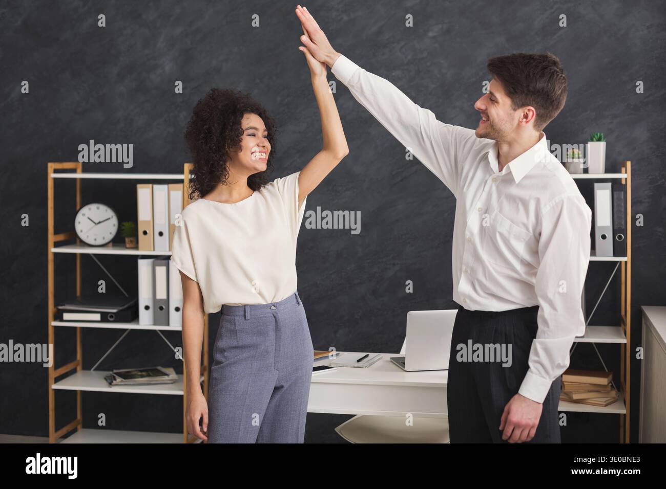 Colleagues giving high five at office Stock Photo