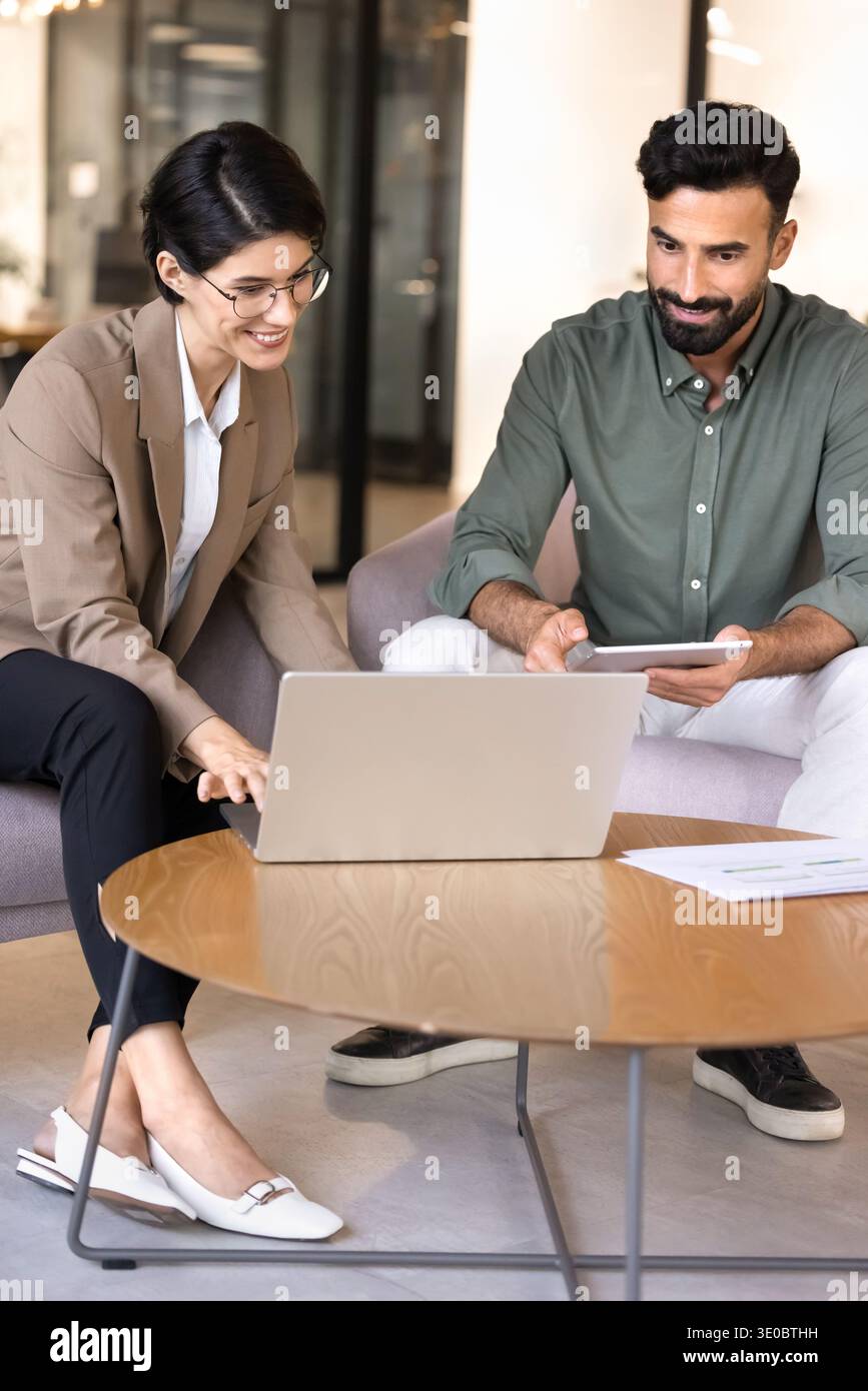 Colleagues collaborating on business project using laptop and tablet Stock Photo