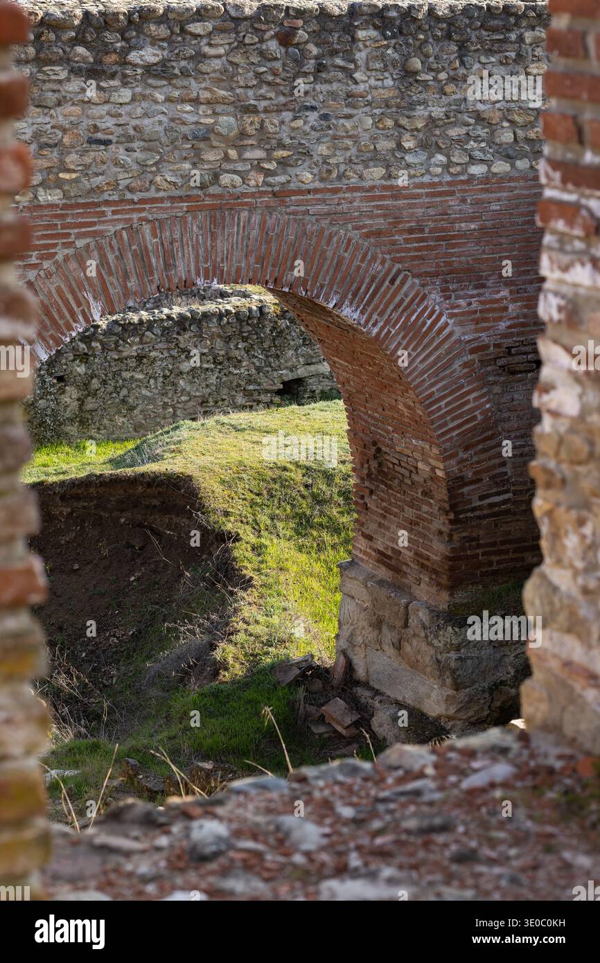 ancient roman brick archway view through stone ruins with sunlit green ...