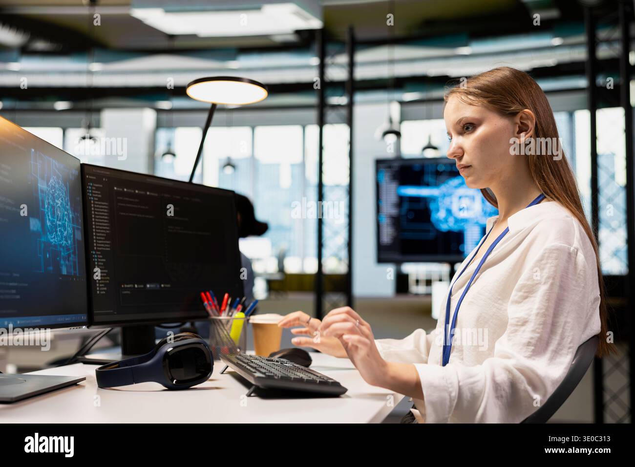 Young female programmer in office using AI scripts, automating repetitive tasks. Junior developer using artificial intelligence technology to speed up feature implementation Stock Photo