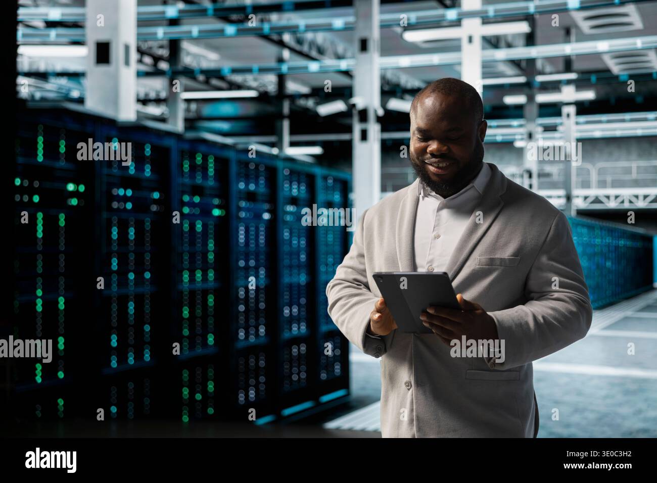 Smiling data center engineer using tablet to protect servers from exploitable software vulnerabilities, auditing systems. Happy cybersecurity expert using device, looking for bugs slowing down servers Stock Photo
