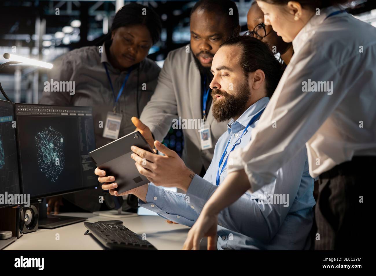 Team of software developers using computer in server farm, analyzing data. Data center office coworkers examining equipment using devices, ensuring system integrity and security Stock Photo