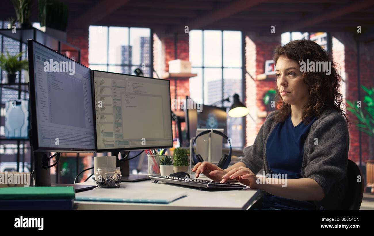 Software expert at workstation programming on pc and writing lines of code, using coding tools and a terminal window interface. Woman debugging software for web development. Camera A. Stock Photo
