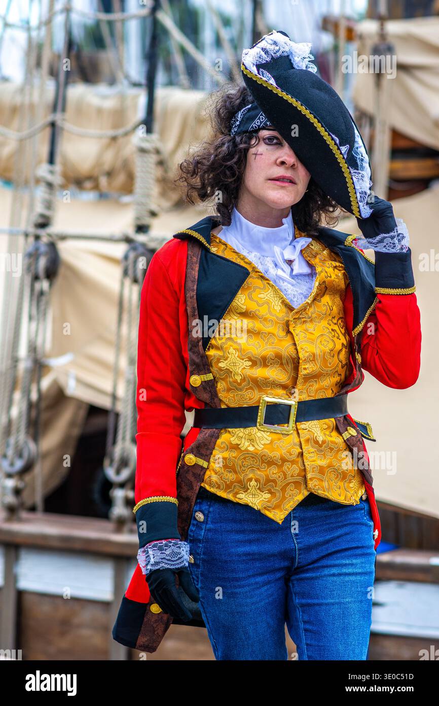 Woman dressed as a pirate captain in a bicorn hat, red jacket and