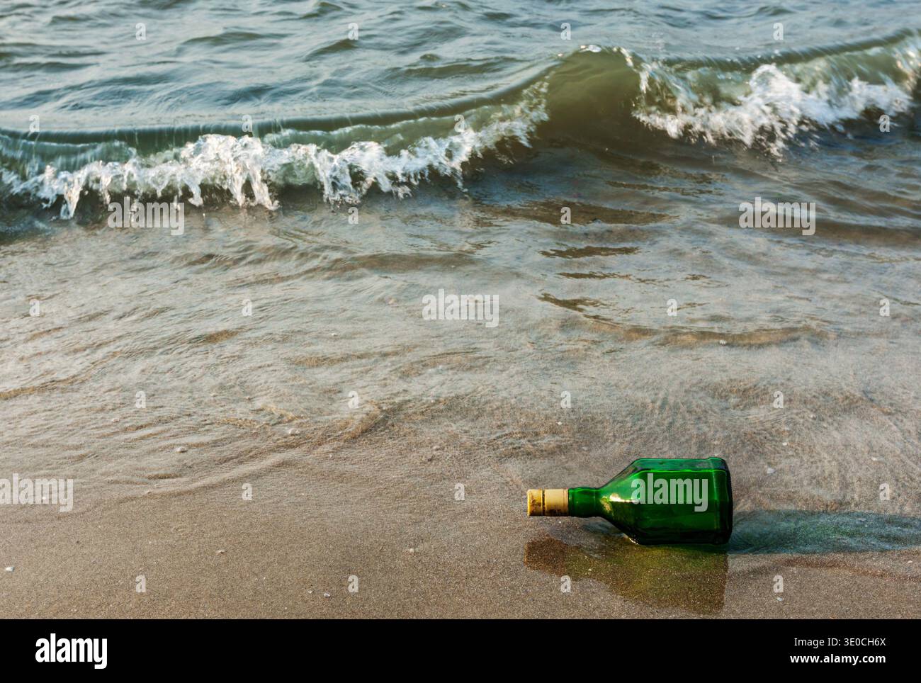 Message bottle on beach in waves Stock Photo