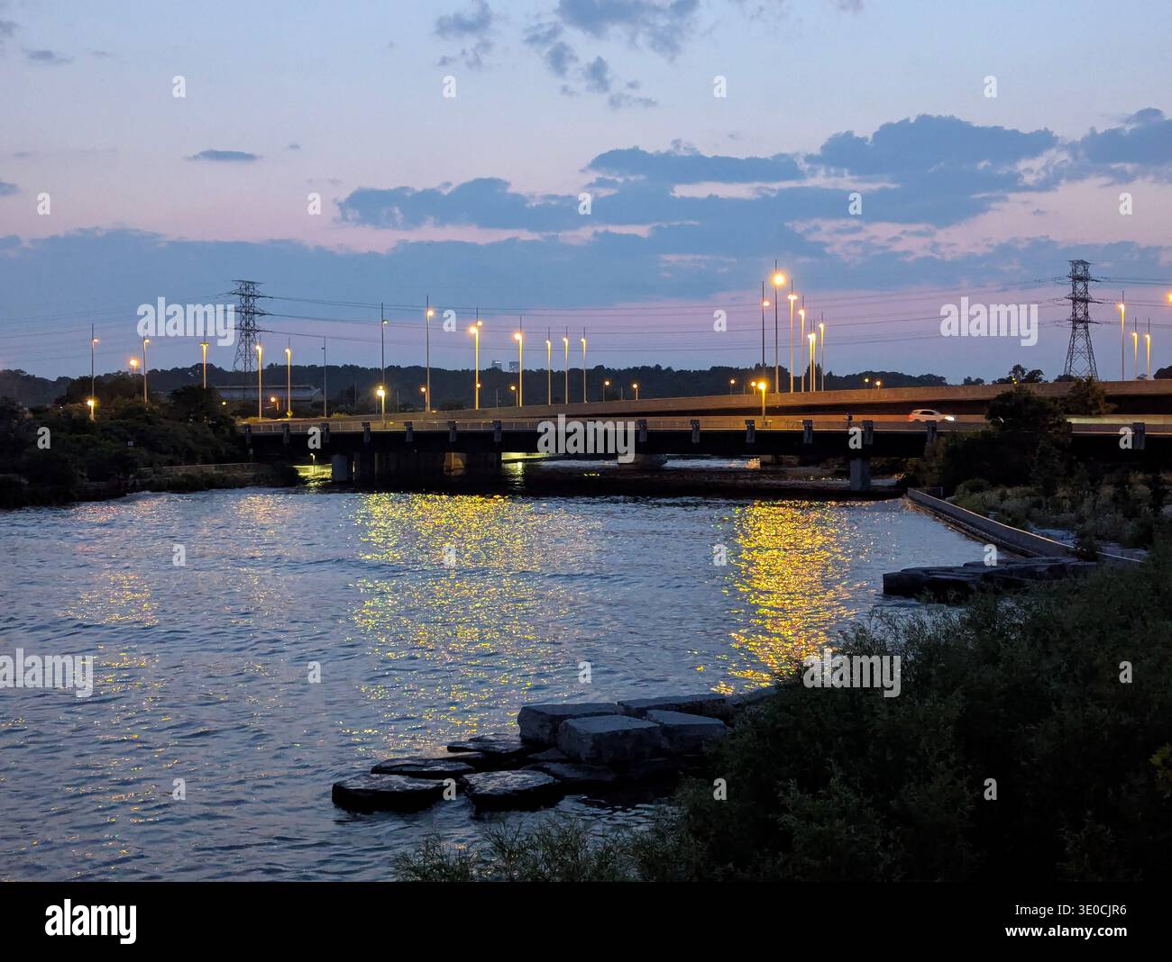 Toronto Infrastructure at Night: Gardiner Expressway Bridge over Humber River with Golden Light Reflections on Water at Twilight, Ontario, Canada. - Smartphone Captured Stock Image