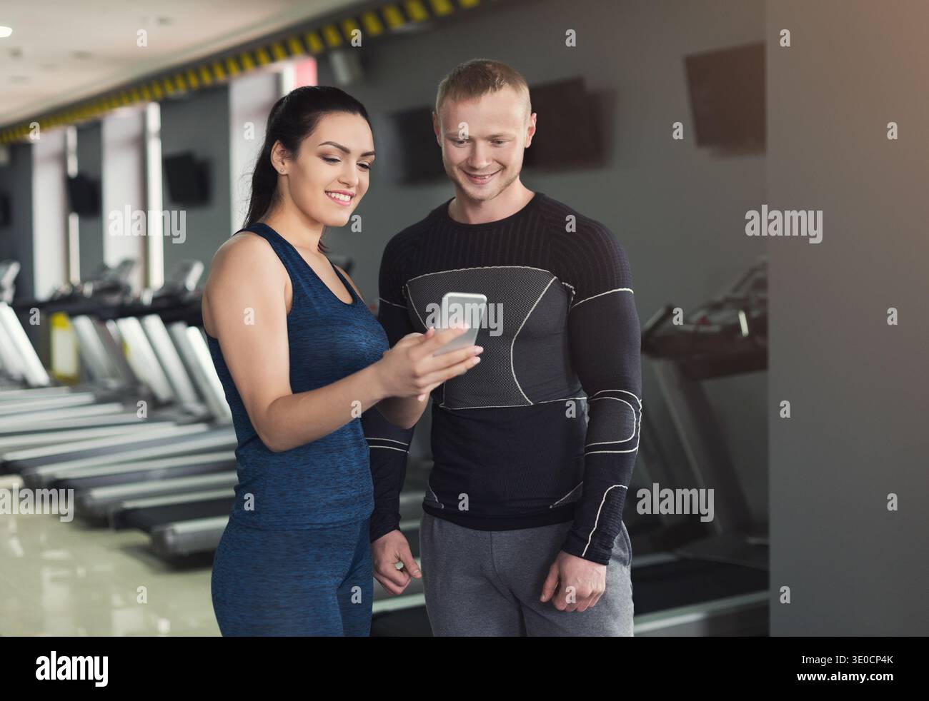 Young couple using smartphone in gym Stock Photo