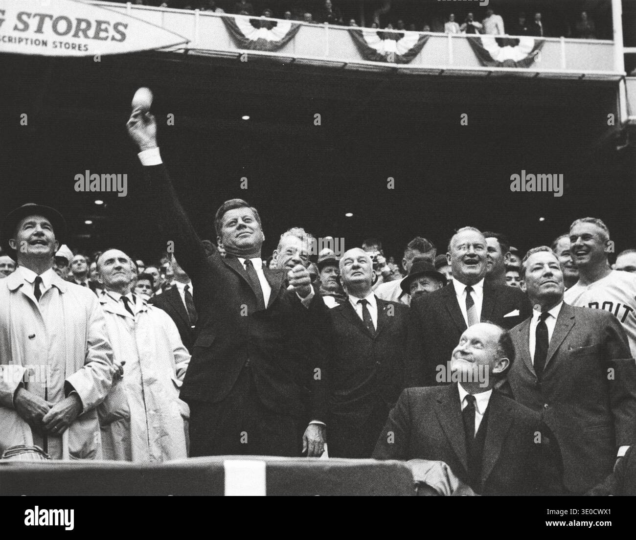 President John F. Kennedy throws the first pitch of the 1962 baseball season. (L-R) Special Assistant to the President Dave Powers; Senator Mike Mansfield of Montana; President Kennedy; Senator Everett Dirksen of Illinois (looking over President Kennedy’s shoulder); Representative Charles Halleck of Indiana; Joseph Cronin, President of the American League of Professional Baseball Clubs; Secretary of the Treasury C. Douglas Dillon (seated in front); General Elwood “Pete” Quesada, majority owner of the Washington Senators; Bob Scheffing, Manager of the Detroit Tigers. Those partially visible in Stock Photo