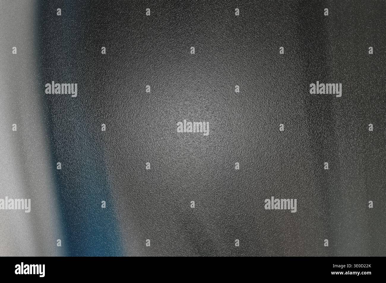 A slightly out-of-focus image shows a dark gray surface with subtle texture and a hint of blue along the left edge. The lighting is uneven, creating a Stock Photo
