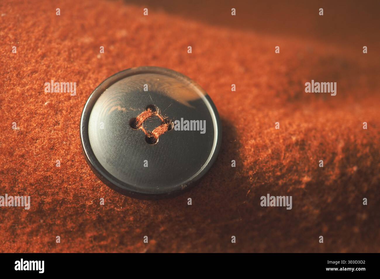 Black button on a brown fabric surface with soft texture Stock Photo