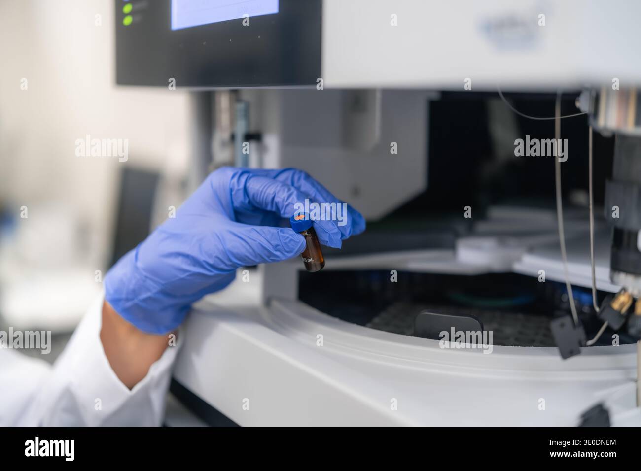 Conducting precise sample analysis using a brown vial within an advanced HPLC system. The workspace features modern equipment and digital displays, reflecting a systematic workflow. Stock Photo