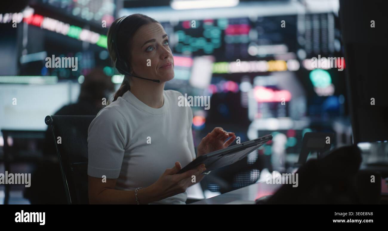 Female Trader Works in Modern Stock Exchange. Woman Interacts With Digital Tablet While Monitoring Complex Market Data Across Large Screens. Concept of Financial Analytics, Professional Multitasking. Stock Photo